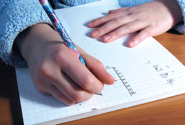 Photo: a photo of a child’s hands doing math homework