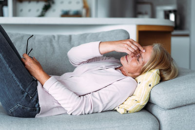 Photo of woman laying on a couch not feeling well.