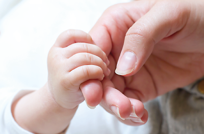 Newborn baby grasping mother’s finger.