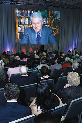 Photo of former U.S. President Bill Clinton appearing on a large TV screen via satellite hook-up at APA’s 2013 annual meeting.