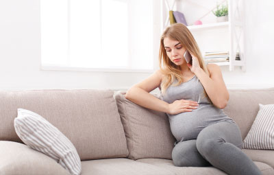 Photo: Pregnant woman on a couch talking on her cell phone
