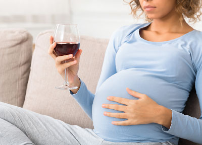 Photo: pregnant woman drinking a glass of wine