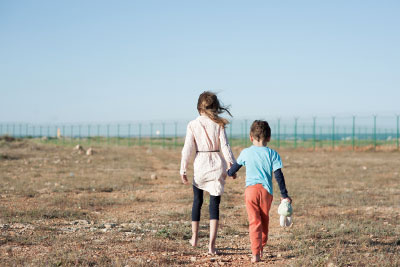 Photo: Two refugee children hold hands as they walk through the hot desert in Mexico toward the U.S. border