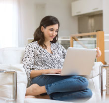 Photo: Young Lady happily working on a laptop seating on a armchair