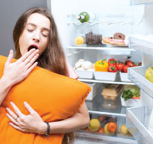 Photo: a sleepy woman in front of open refrigerator