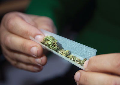 Photo: hands rolling up a marijuana cigarette