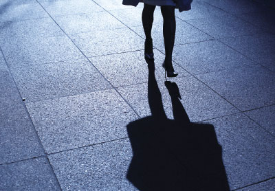 Photo: Woman's legs walking on a sidewalk at night"