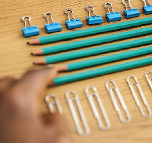 Photo: Person aligning pencils binder clips and paper clips