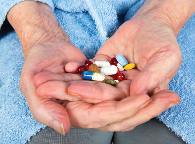 Photo: Elderly hands holding a large number of pills