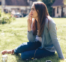 Photo: girl in park sitting on grass and smoking a cigarette