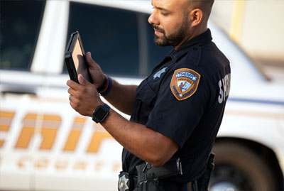 Photo: Sergeant Jose Gomez checks his iPad –which has ready access to mental health specialists—before he heads out on patrol.