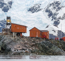 Photo: houses on the edge of water sorrounded by glaciars