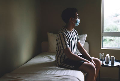 Photo: hospital patient with mask sitting on a bed