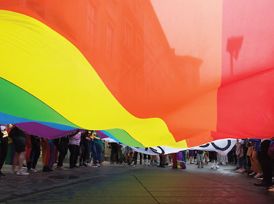 Photo: Crowd carring a LGBTQ+ flag