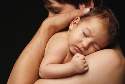 Photo: Man hugging a sleeping infant