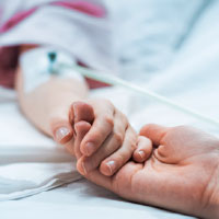 Graphic: holding hand of a child in hospital bed