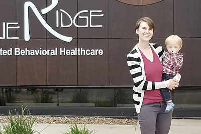 Shea Jorgensen, M.D., with son Finn, outside Prairie Ridge Integrated Behavioral Health Clinic, in Mason City, Iowa.