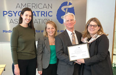 Photo: APA President Rebecca Brendel, M.D., J.D. (right), honors Robert Trestman, Ph.D., M.D., for his work as chair of the Presidential Workgroup on a Roadmap for the Future of Psychiatry. He presented the workgroup’s final report at the Board of Trustees’ March meeting. At left are Agathe Farrage, senior manager of APA’s Policy, Programs, Partnerships Division; and Kristin Kroeger, the division’s chief. They provided staff support to the workgroup.