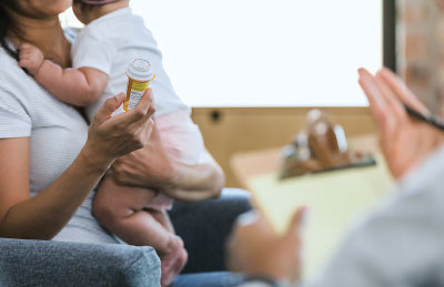 mother holding a baby talking with a docort about medications