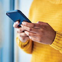 person wearing a yellow sweater checking a cell phone
