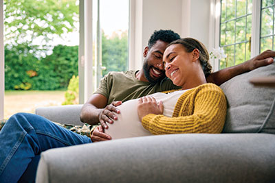 Image of a pregnant couple relaxing on a couch.