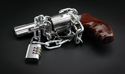 Photo of a revolver wrapped with a chain and a padlock.