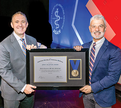 Photo of APA President Petros Levounis, M.D., M.A., accepting the John P. McGovern, M.D., Award of the American Society of Addiction Medicine (ASAM) from ASAM President Brian Hurley, M.D.
