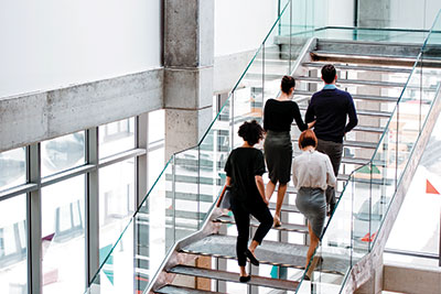 Photo of professionals walking up stairs in a hospital or office style building.